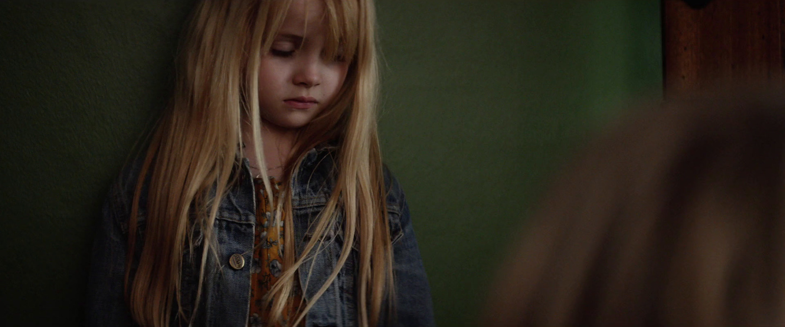 a young girl with long blonde hair standing in front of a mirror