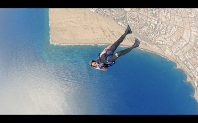 a man flying through the air while riding a parachute