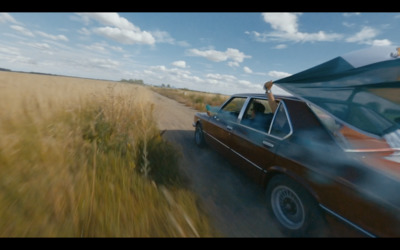 a car driving down a road next to a field