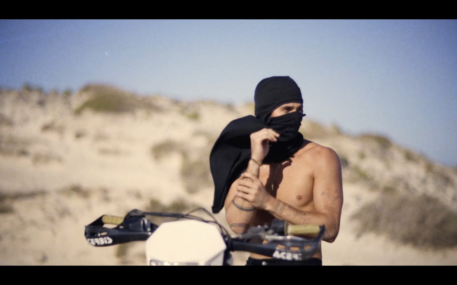 a shirtless man wearing a bandana on a motorcycle