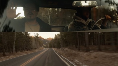 a man driving a car down a road next to a forest