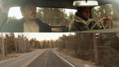 a man driving a car down a road next to a forest