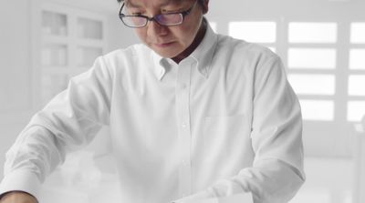 a man in a white shirt cutting a cake