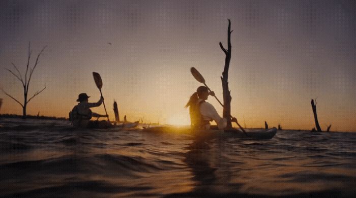 a couple of people riding on top of a kayak