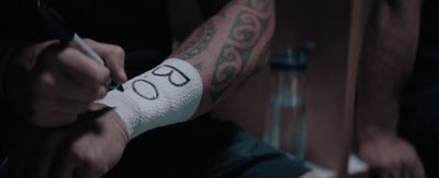 a man with a tattoo on his arm writing on a piece of paper