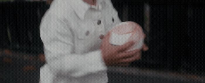 a little girl in a white shirt holding a pink ball