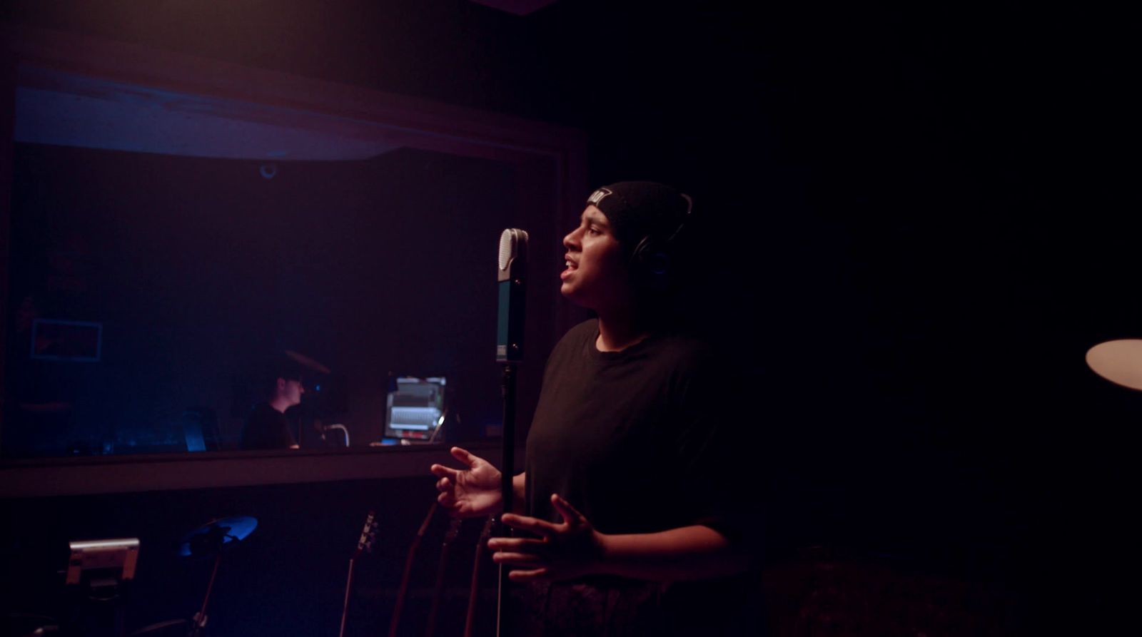 a woman standing in front of a microphone in a dark room