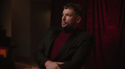 a man in a black jacket and a red shirt