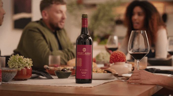 a group of people sitting around a table with a bottle of wine