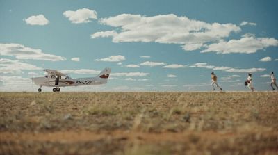 a group of people walking across a dry grass field