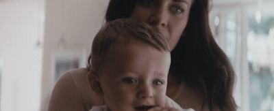 a woman brushing her teeth with a baby in front of her