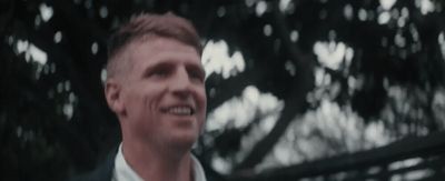 a man in a suit and tie smiles at the camera