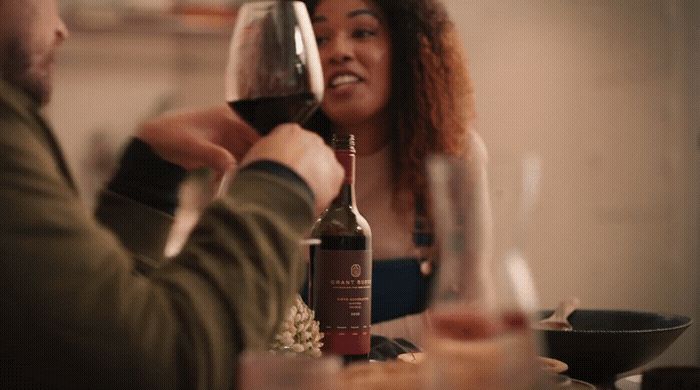 a man and a woman sitting at a table drinking wine