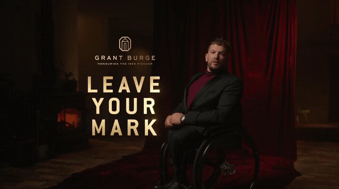 a man sitting in a wheel chair in front of a red curtain