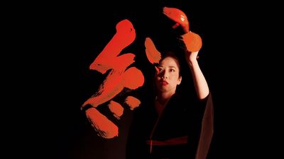 a woman holding up a pair of orange scissors