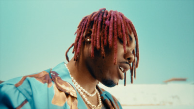 a man with red dreadlocks and a pearl necklace