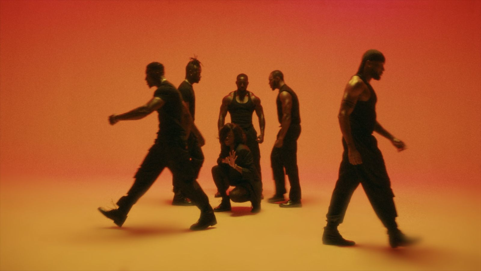 a group of men walking across a red and orange background