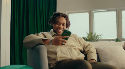 a man sitting on a couch looking at a cell phone