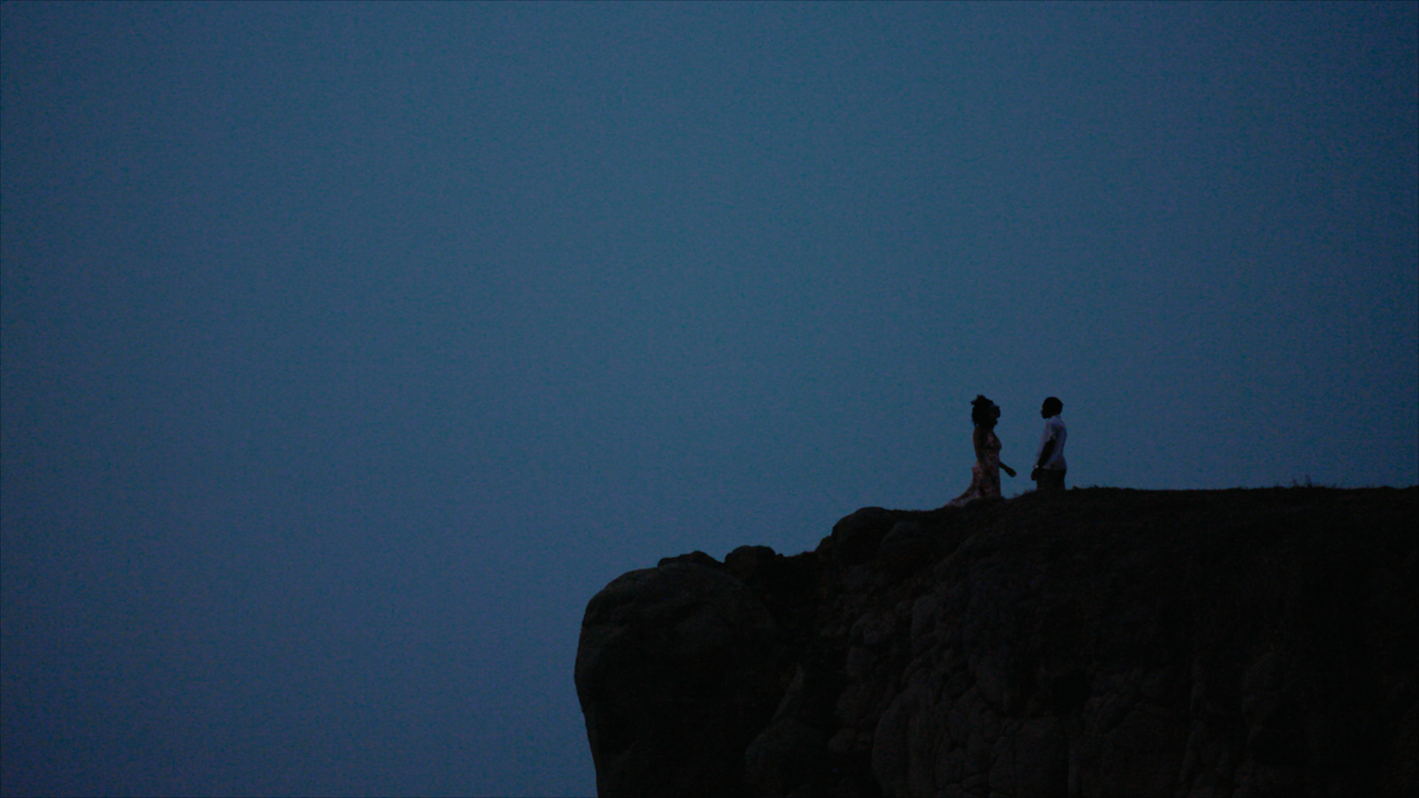 a couple of people standing on top of a cliff