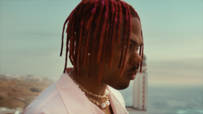 a man with red dreadlocks standing near the ocean