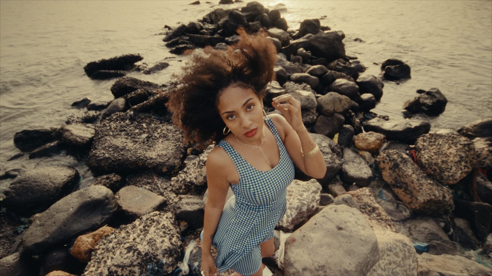 a woman standing on rocks near the water