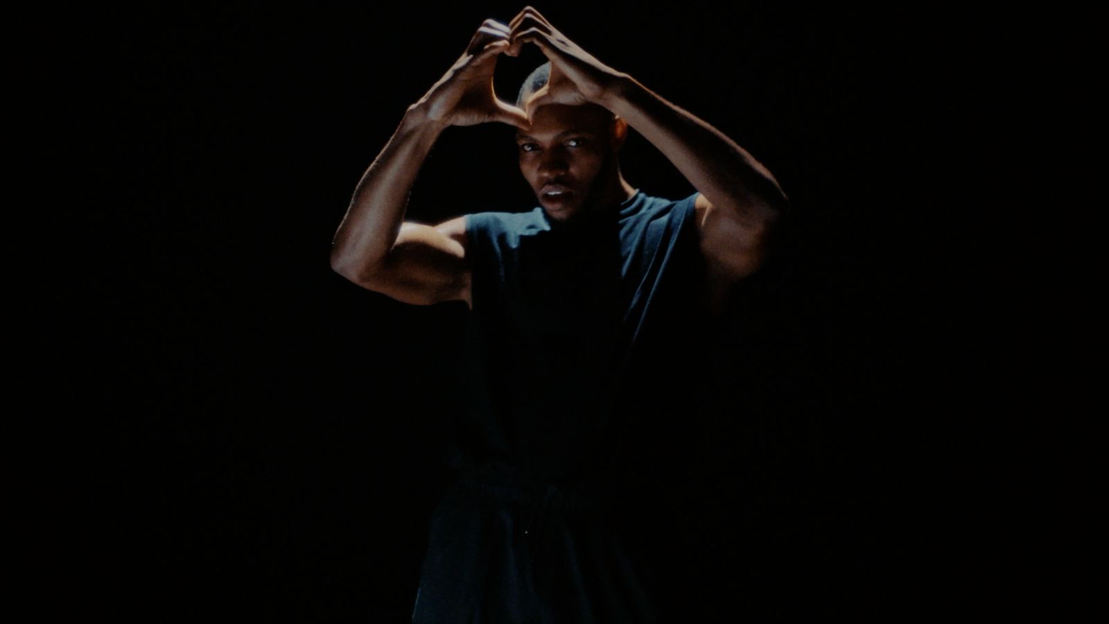 a man standing in the dark with his hands on his head