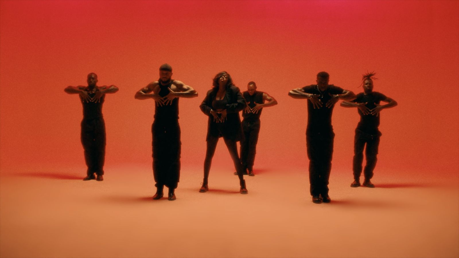 a group of people standing in front of a red background