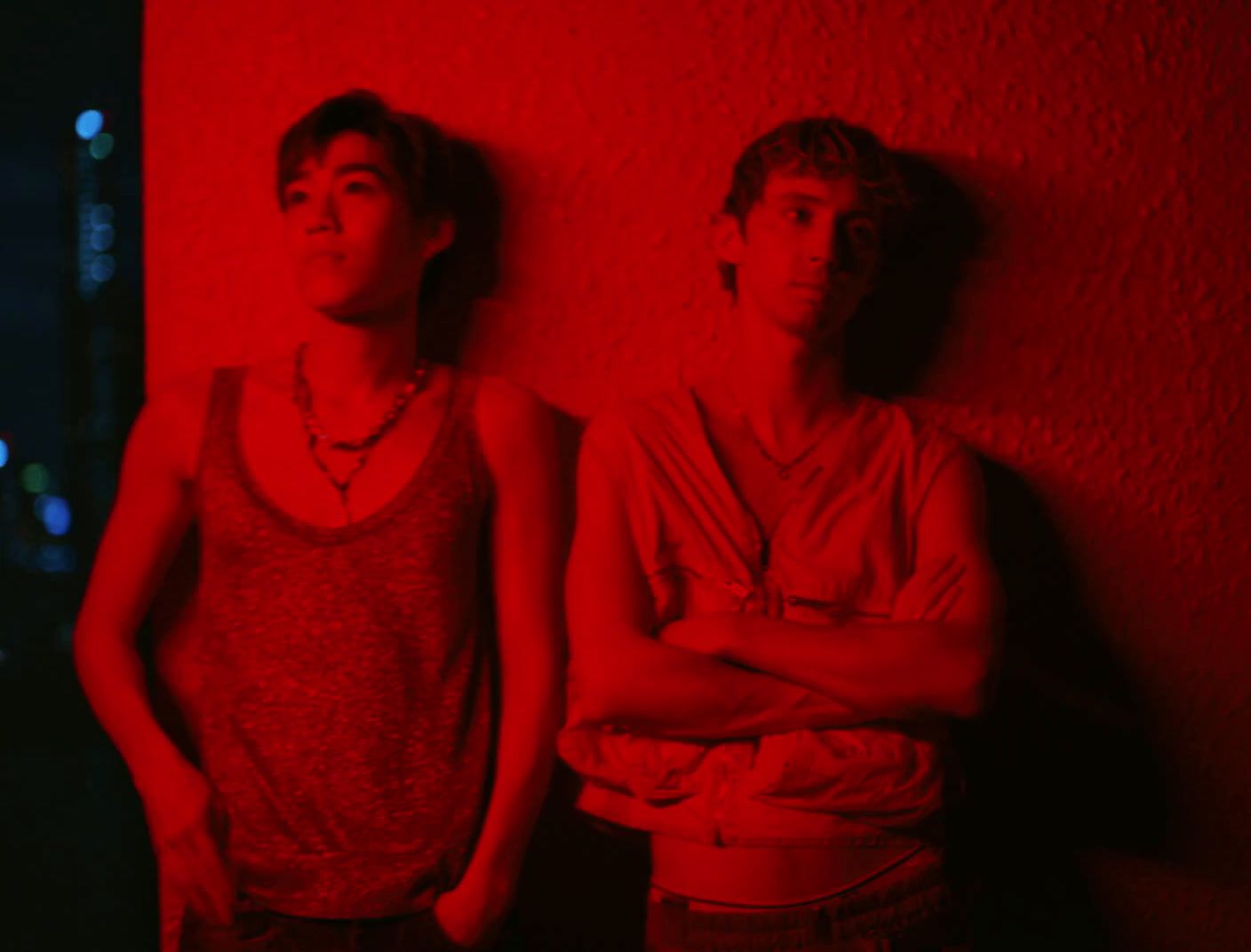 two young men standing in front of a red wall