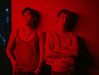 two young men standing in front of a red wall