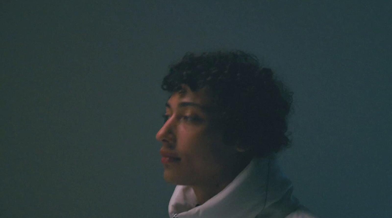 a woman with curly hair wearing a white coat