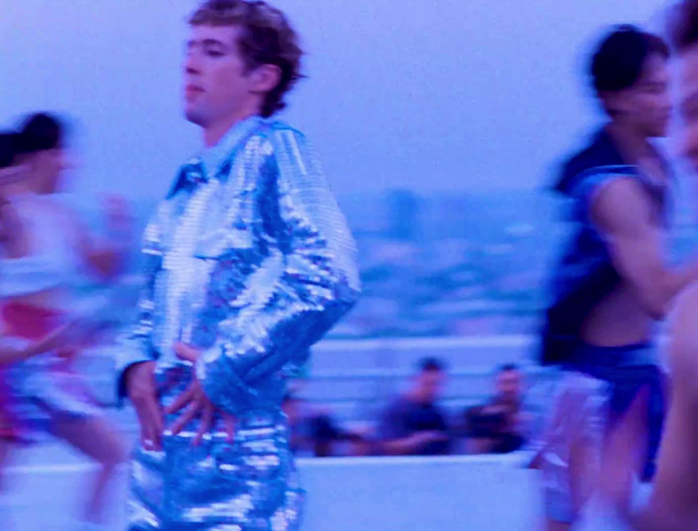 a man in a shiny blue suit standing in front of a group of people