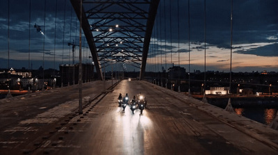 a group of people riding motorcycles across a bridge