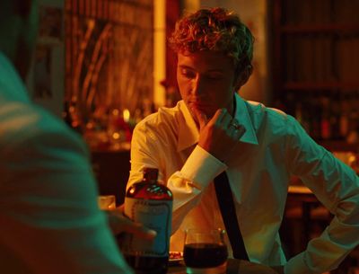 a man sitting at a table with a bottle of wine