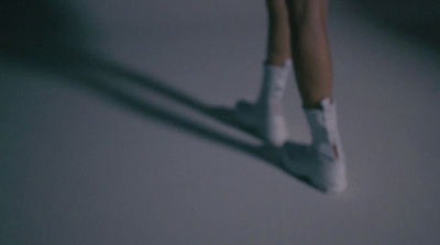 a close up of a person's legs wearing white shoes