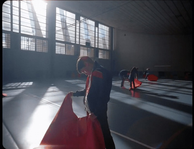 a man standing in a gym holding a red bag