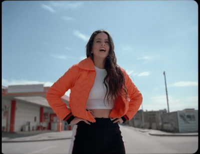 a woman in an orange jacket standing in front of a building