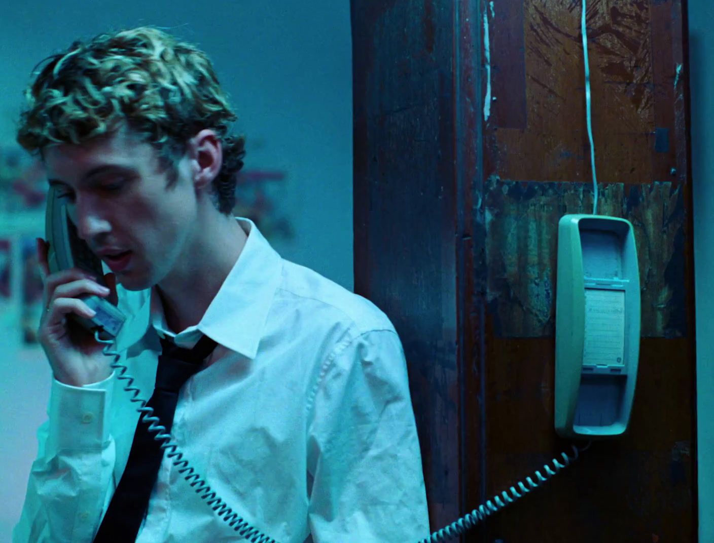 a young man talking on a telephone while wearing a tie