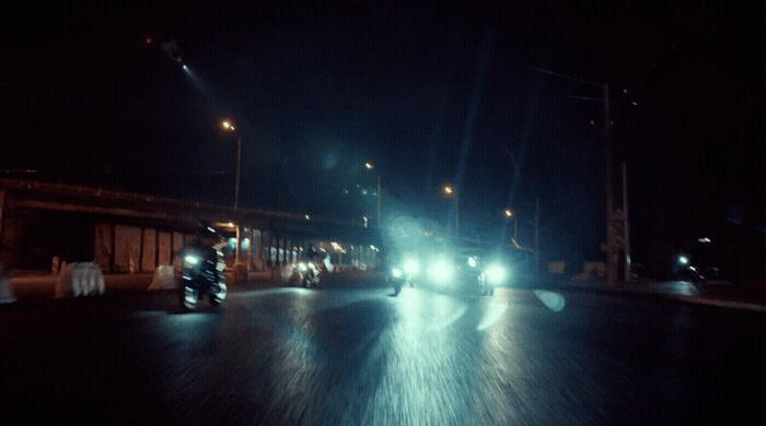 a couple of cars driving down a street at night