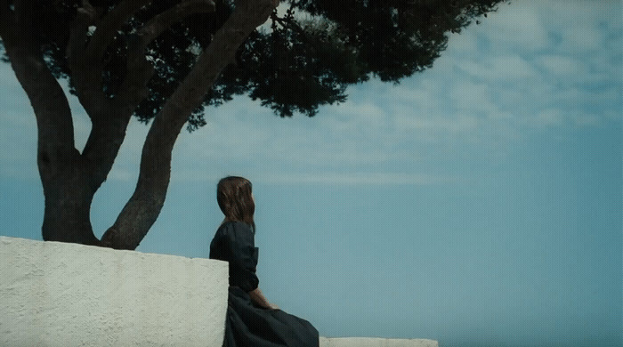 a woman sitting on a wall next to a tree