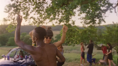 a man and a woman dancing in front of a car