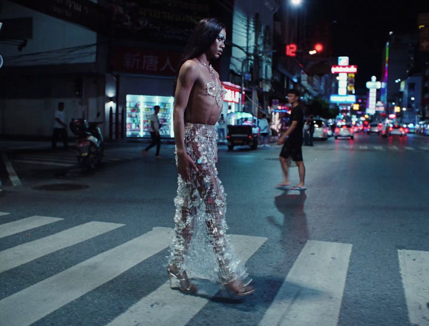 a woman standing on the side of a street at night