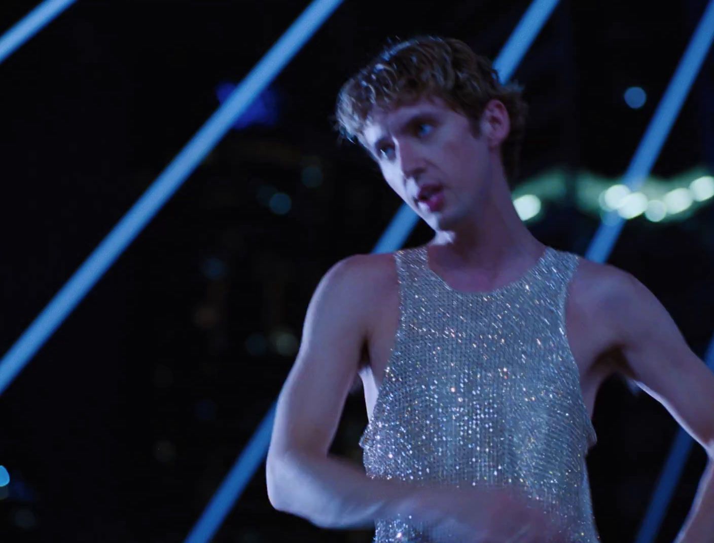 a man in a silver dress standing in a dark room