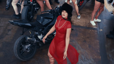 a woman in a red dress standing next to a motorcycle