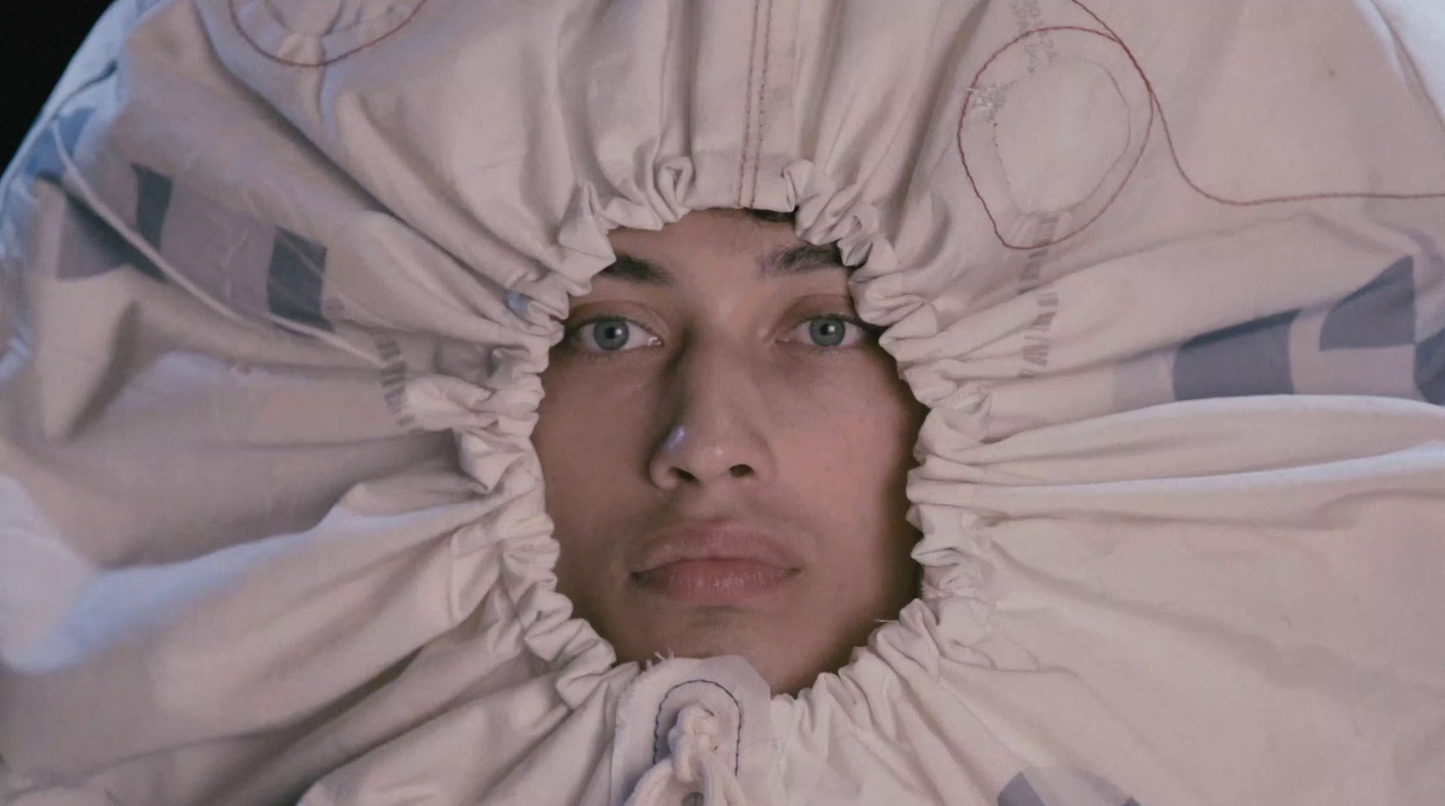 a woman is hiding under a white blanket