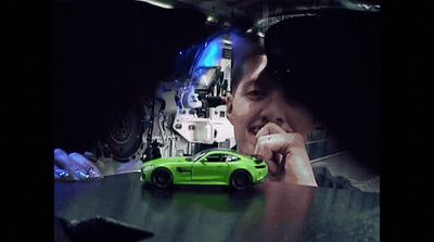 a green car is parked in front of a man