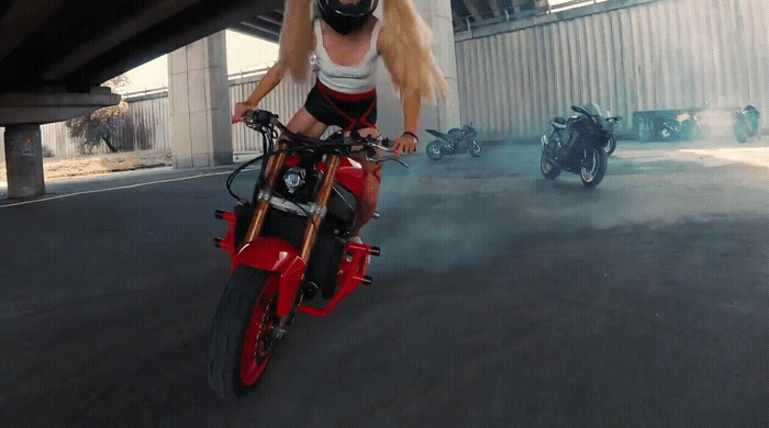 a woman riding a red motorcycle down a street