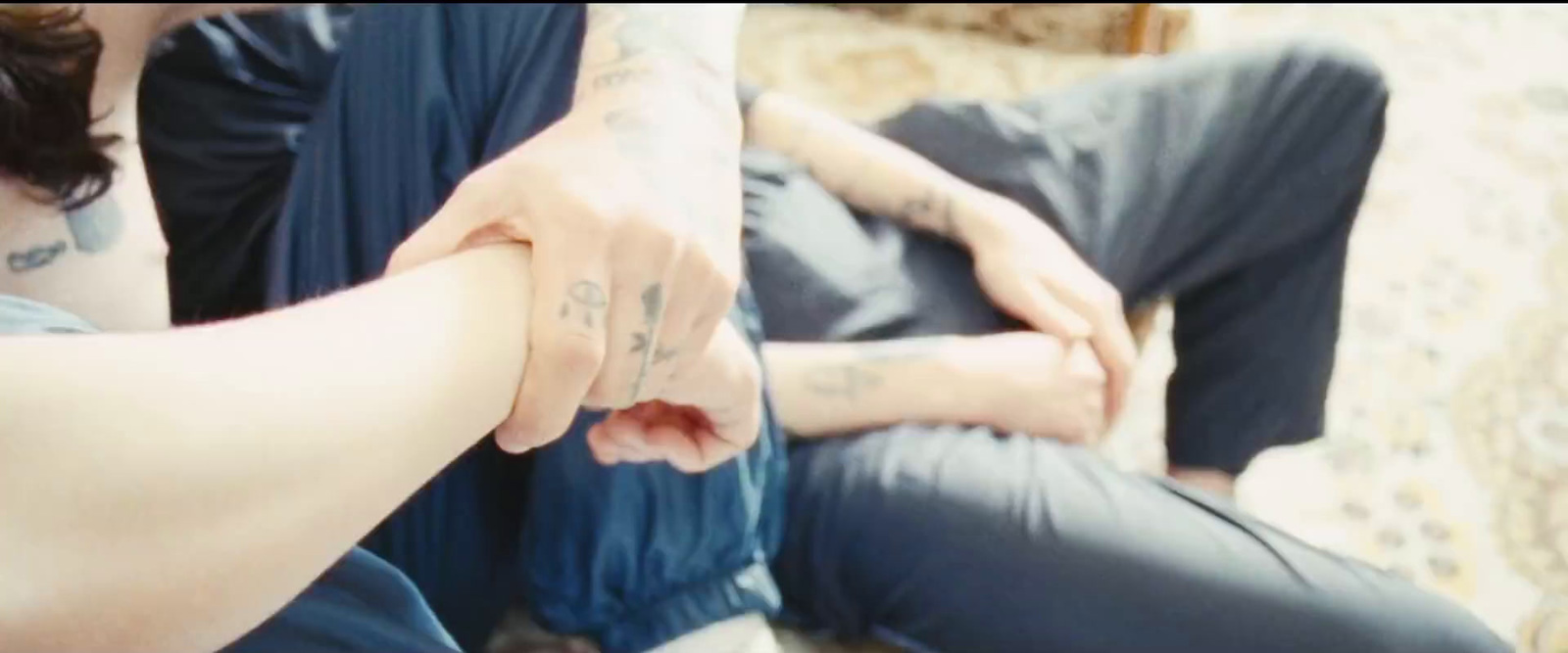 a man with tattoos on his arm sitting next to a woman