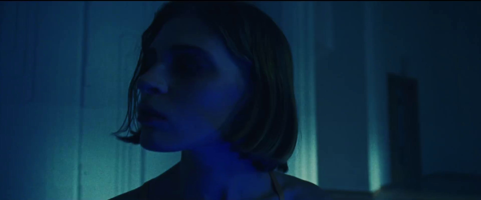 a woman standing in a dark room with a blue light on her face