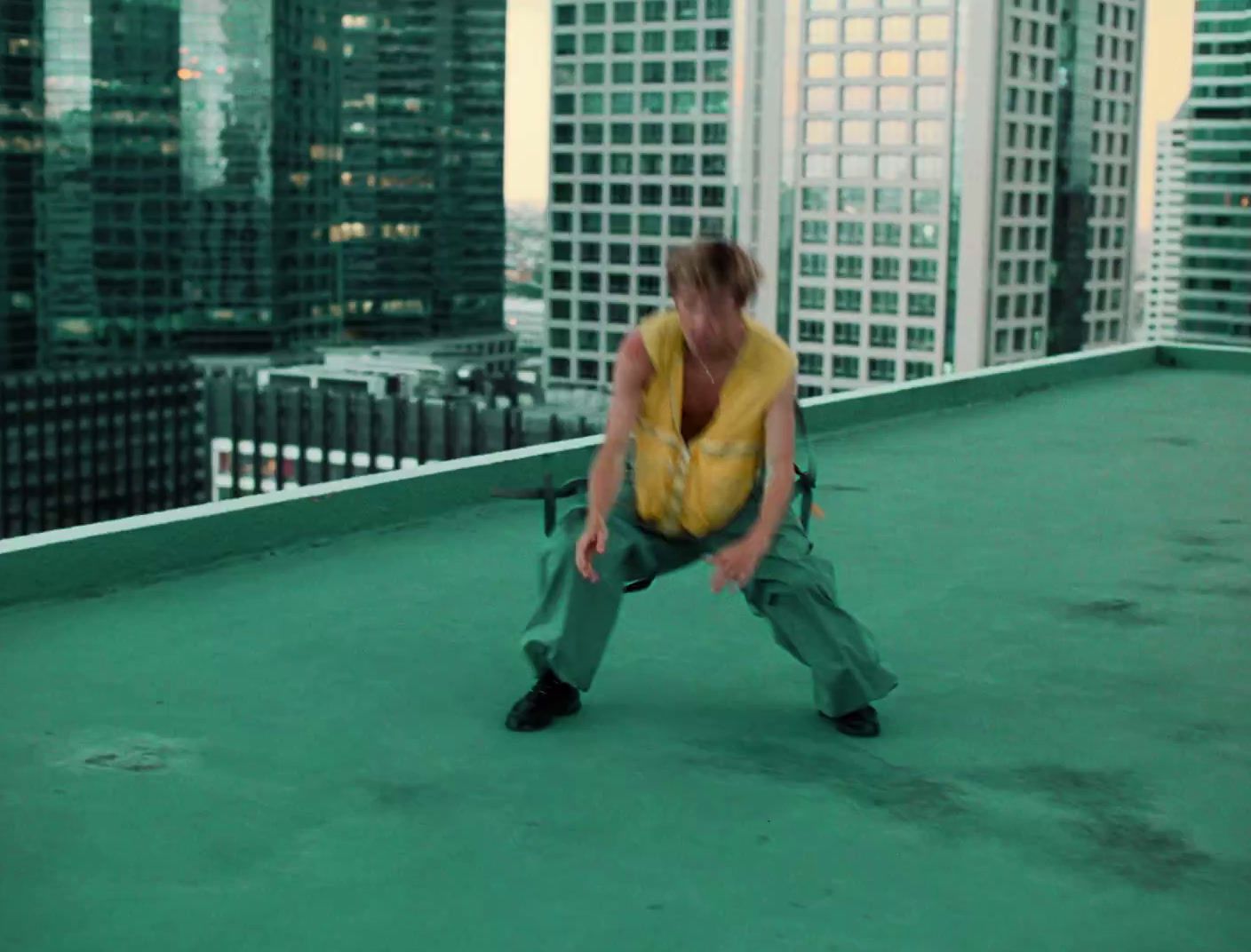 a man kneeling down on a roof in a city