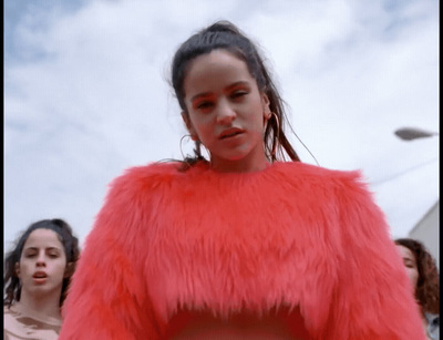 a woman in a red fur coat standing in front of a group of people